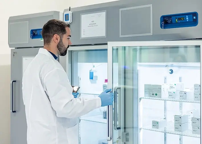 Ein Mann stellt Medikamente in einen großen Kühlschrank